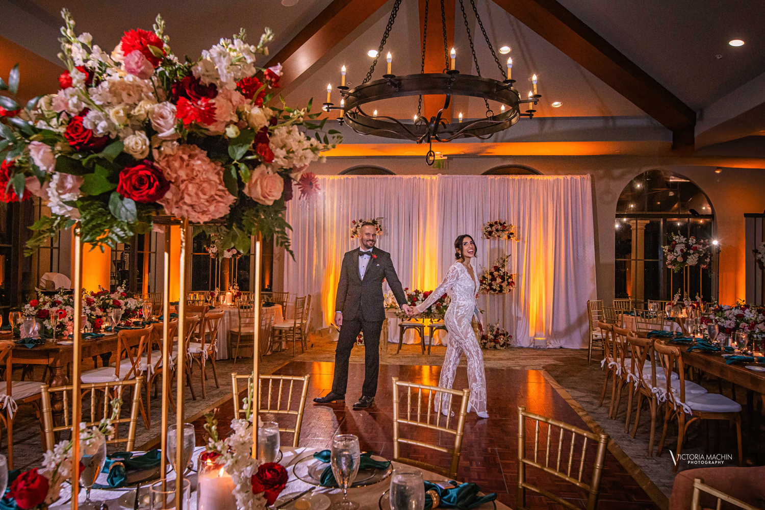 Bride and groom holding hands inside their beautifully decorated wedding reception space at Parkland Country Club.