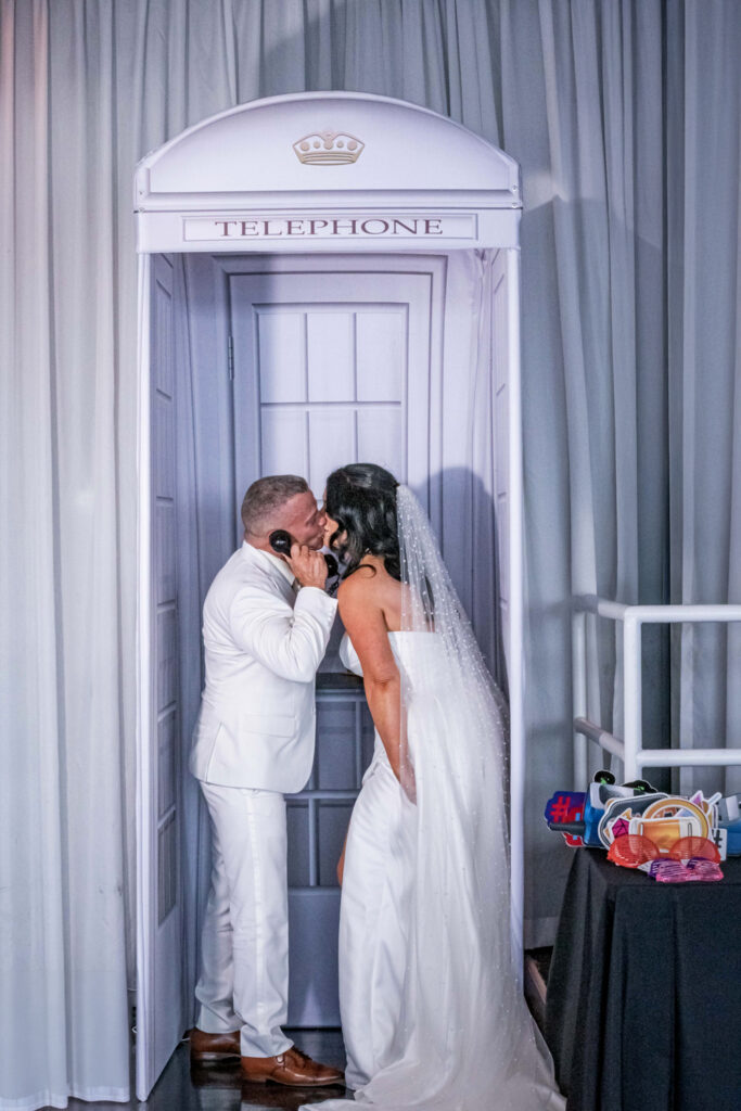 Bride and groom in white kissing inside a modern white audio guest book booth at a luxury South Florida wedding, designed by Zeta Event Productions.
